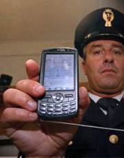 un operatore di polizia mostra uno dei telefonini sequestrati