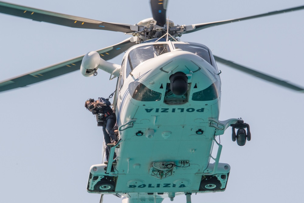 Il fotoreporter Massimo Sestini imbracato fuori dall'elicottero della Polizia di Stato mentre sorvola Tavolara (OL)